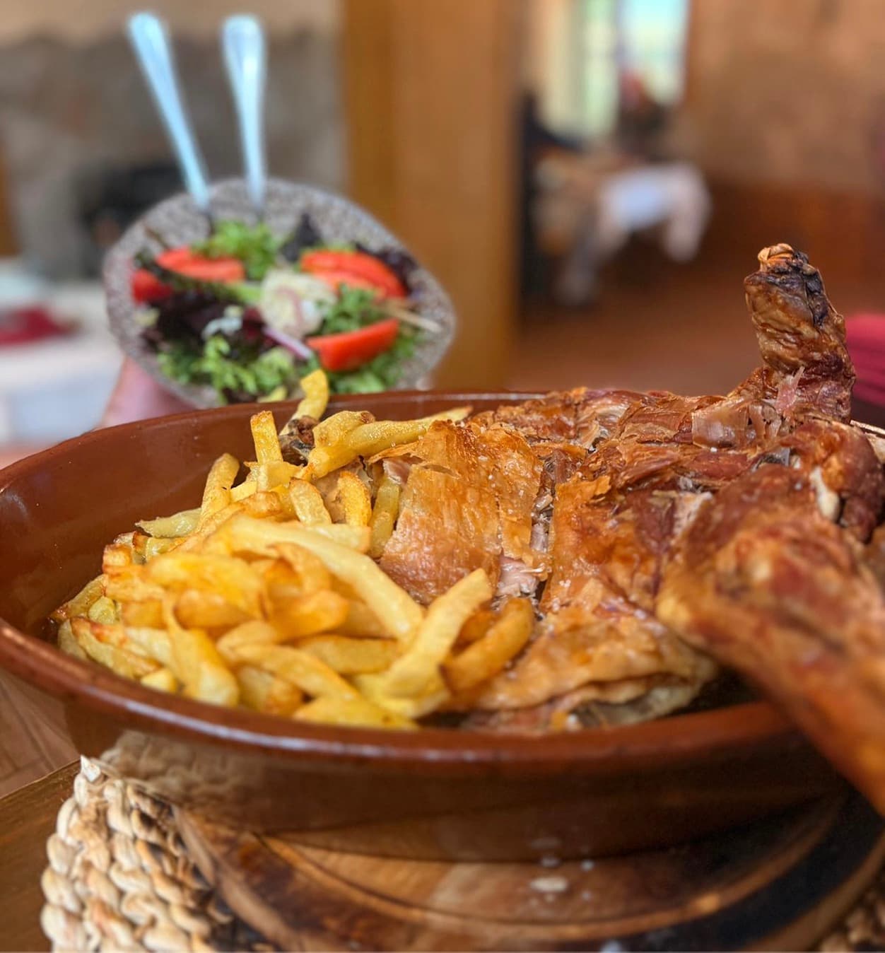 Ración de cordero asado con guarnición de patatas.